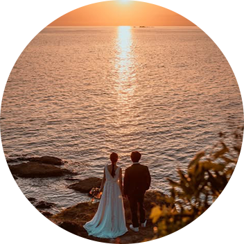 崖の上で夕陽を眺める新郎と新婦